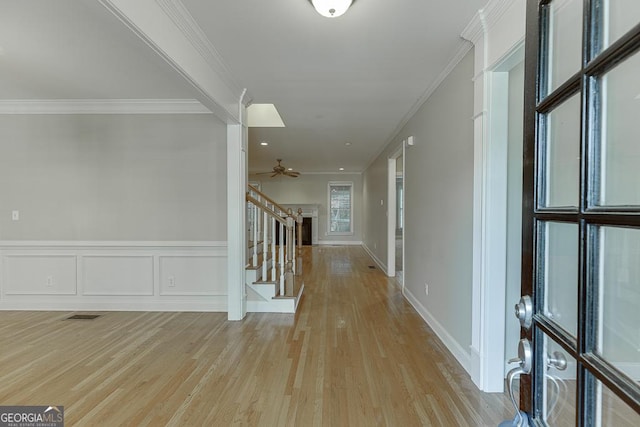 hall with light wood-type flooring and ornamental molding