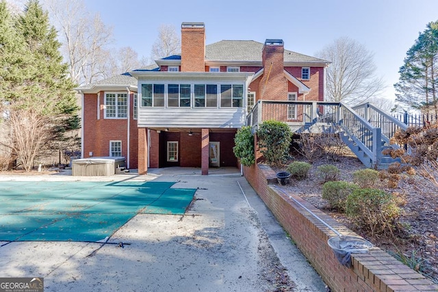 back of house featuring a deck, a patio area, a sunroom, and a hot tub