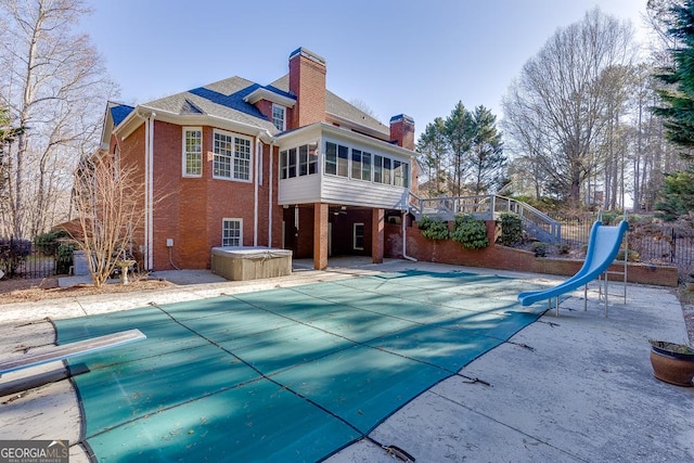 back of property with a pool with hot tub, a patio area, and a sunroom