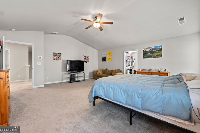 carpeted bedroom with ceiling fan, a walk in closet, a closet, and vaulted ceiling