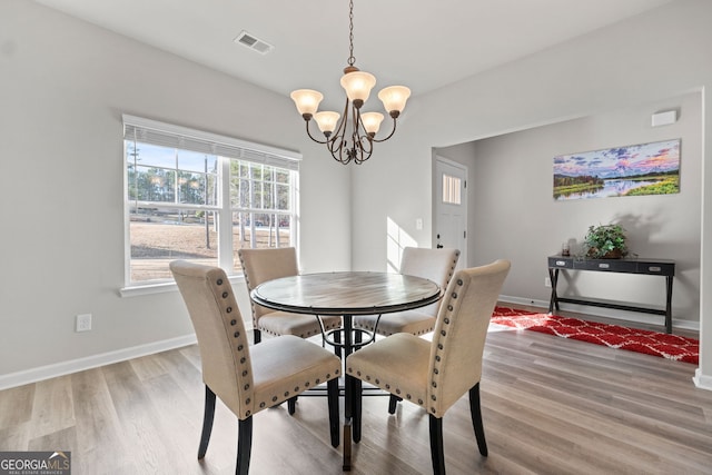 dining space with a notable chandelier and light hardwood / wood-style flooring