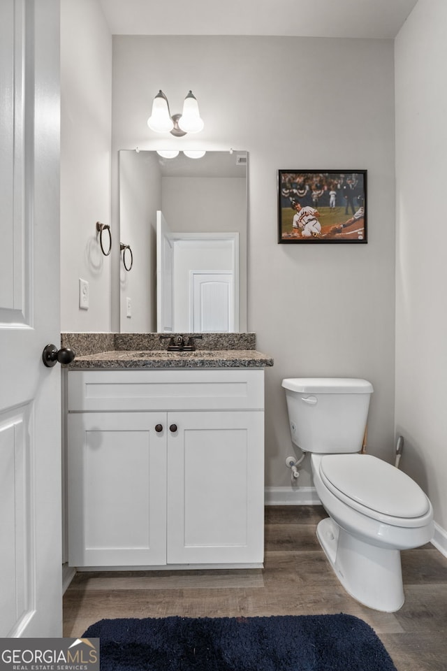 bathroom featuring wood-type flooring, toilet, and vanity