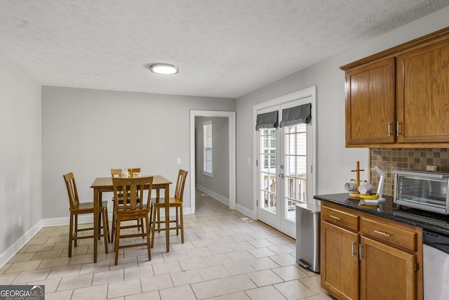 dining area with a textured ceiling, french doors, and light tile patterned flooring