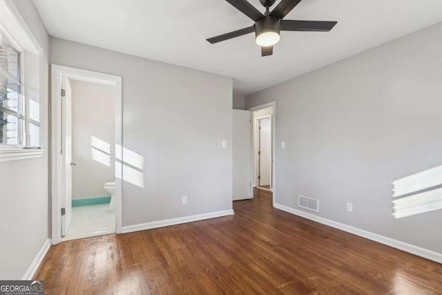 unfurnished bedroom with ensuite bathroom, ceiling fan, and dark hardwood / wood-style flooring