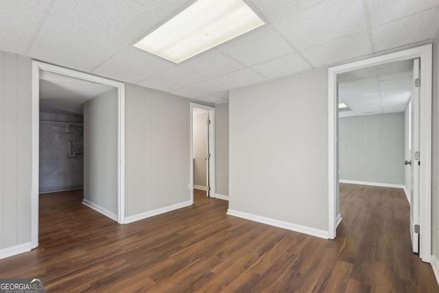 empty room featuring a paneled ceiling and dark hardwood / wood-style floors