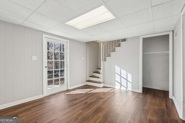 basement with a drop ceiling and dark wood-type flooring