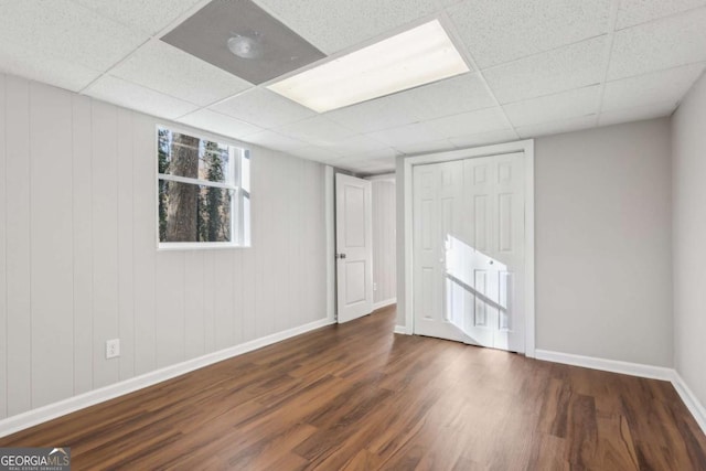 basement with a drop ceiling and dark hardwood / wood-style floors