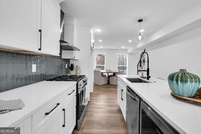 kitchen featuring sink, stainless steel appliances, dark hardwood / wood-style floors, white cabinets, and decorative light fixtures