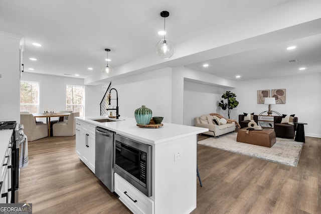 kitchen featuring sink, a center island with sink, appliances with stainless steel finishes, pendant lighting, and white cabinets