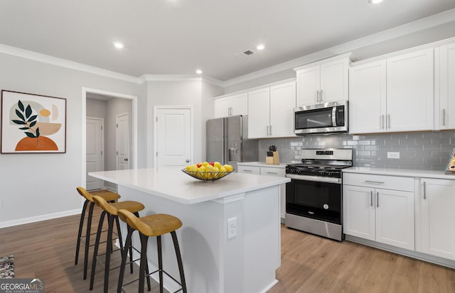 kitchen with appliances with stainless steel finishes, white cabinetry, and a kitchen island