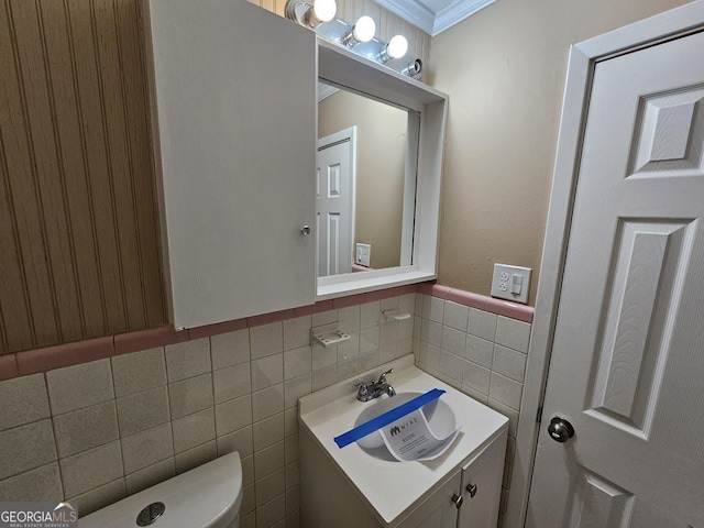 bathroom with toilet, crown molding, tile walls, and vanity