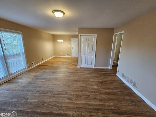 empty room featuring dark hardwood / wood-style flooring and a chandelier