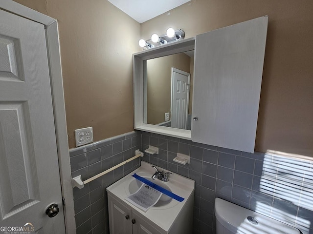 bathroom with toilet, tile walls, and vanity