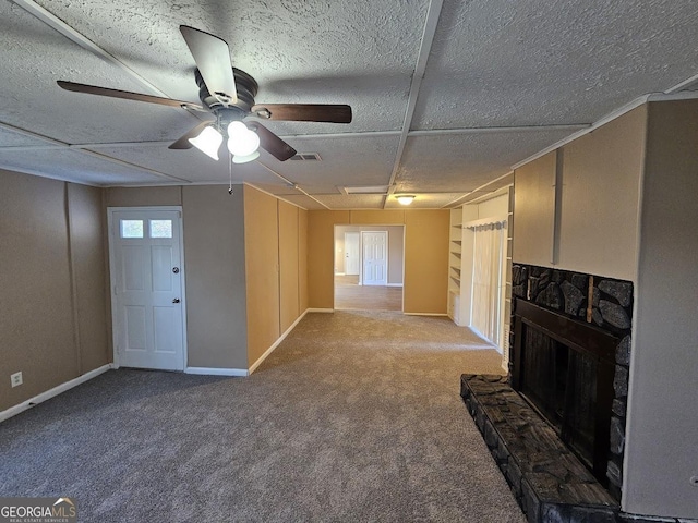 unfurnished living room featuring ceiling fan, a stone fireplace, and carpet flooring