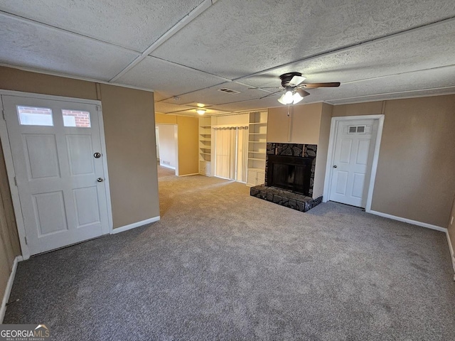 unfurnished living room featuring ceiling fan, a fireplace, and carpet floors