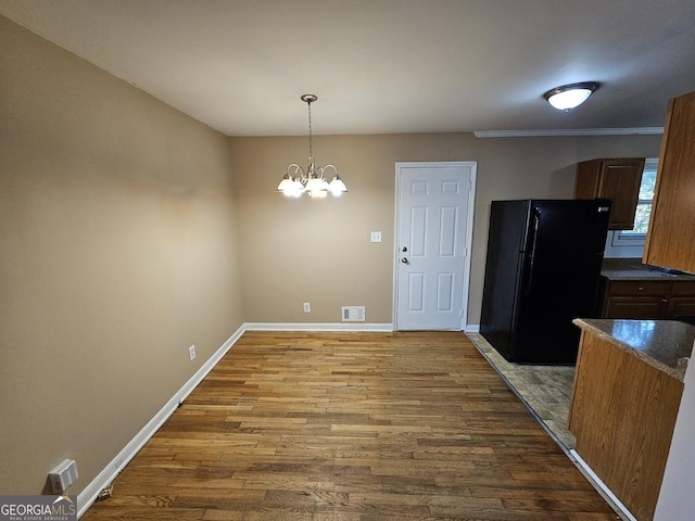 unfurnished dining area with a notable chandelier and hardwood / wood-style floors