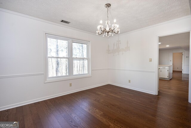 empty room featuring a textured ceiling, an inviting chandelier, crown molding, and dark hardwood / wood-style floors