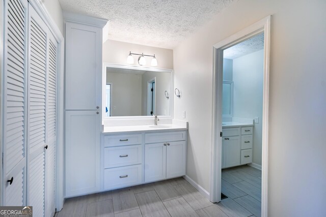 bathroom featuring a textured ceiling, toilet, and vanity