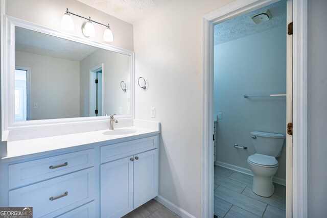 bathroom with toilet, a textured ceiling, a shower with door, and vanity