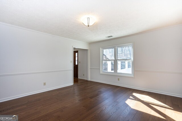 spare room featuring a textured ceiling, dark hardwood / wood-style floors, ornamental molding, and a notable chandelier