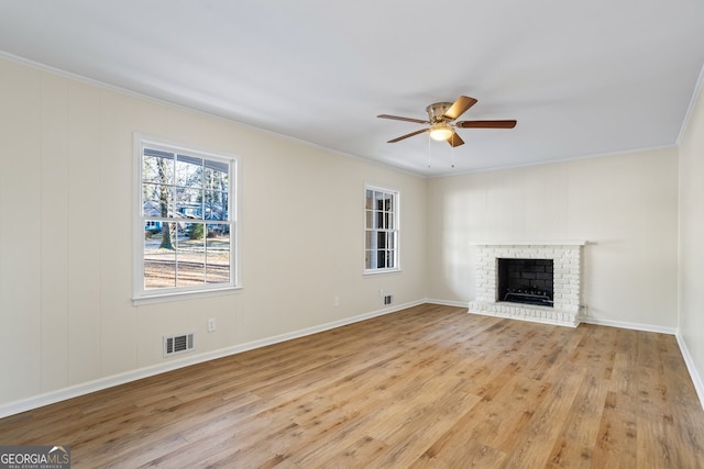 unfurnished living room featuring ceiling fan, a fireplace, crown molding, and light hardwood / wood-style floors