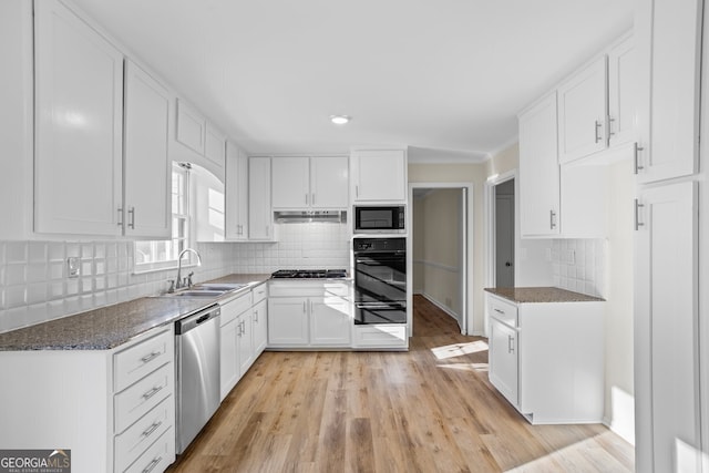 kitchen with stainless steel appliances, backsplash, light wood-type flooring, white cabinets, and sink