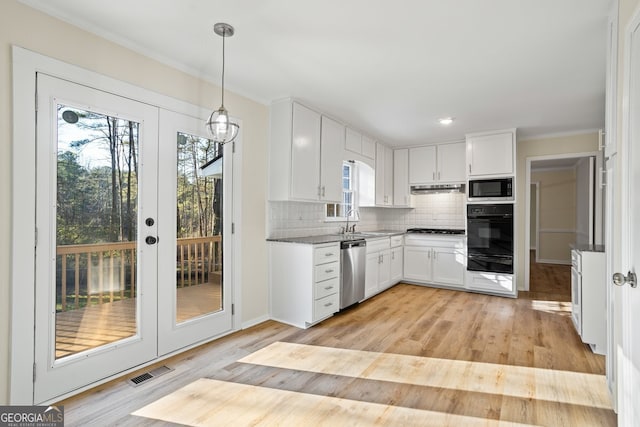 kitchen with appliances with stainless steel finishes, white cabinets, hanging light fixtures, light hardwood / wood-style flooring, and sink