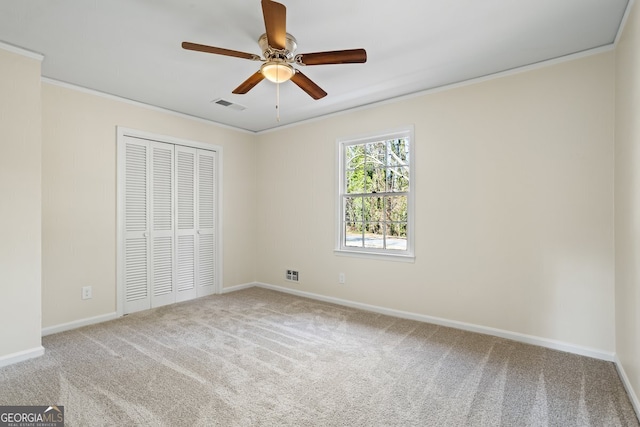 unfurnished bedroom featuring ceiling fan, a closet, ornamental molding, and carpet flooring