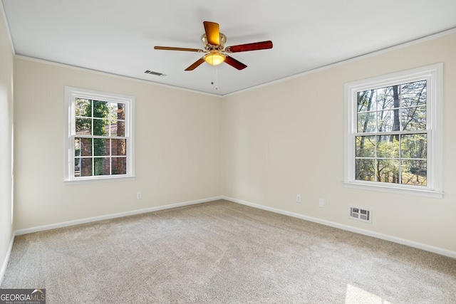 carpeted spare room featuring ceiling fan, plenty of natural light, and crown molding