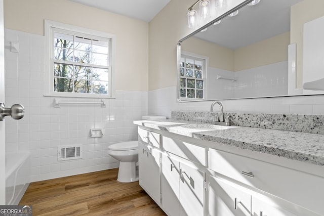 bathroom featuring toilet, vanity, tile walls, and hardwood / wood-style flooring