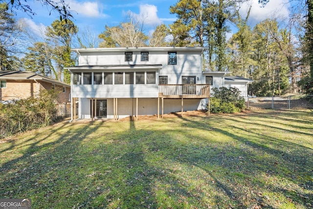 back of property featuring a deck, a sunroom, and a lawn