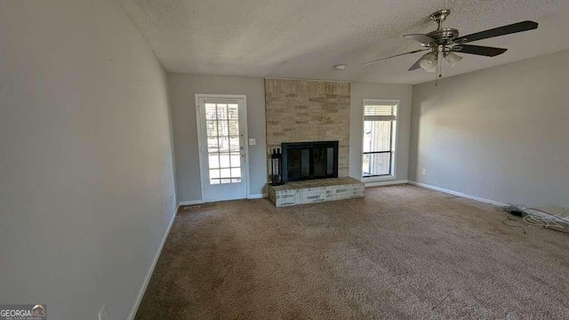 unfurnished living room featuring a textured ceiling, ceiling fan, carpet flooring, and a fireplace