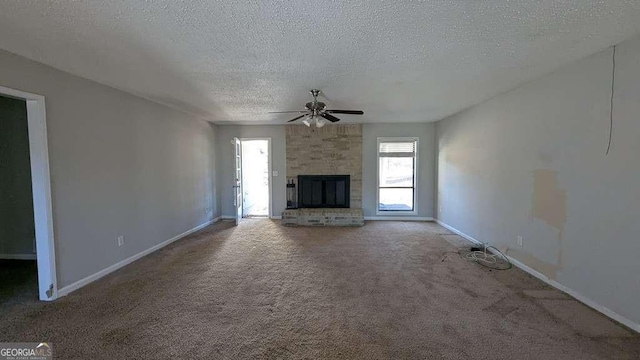 unfurnished living room with carpet, ceiling fan, a fireplace, and a textured ceiling