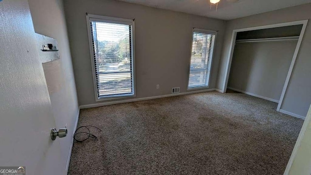 unfurnished bedroom with multiple windows, carpet, and a closet