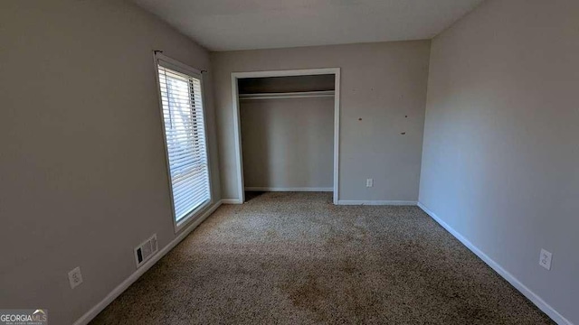 unfurnished bedroom with a closet and light colored carpet