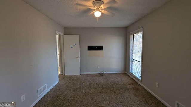 carpeted empty room featuring ceiling fan and a textured ceiling