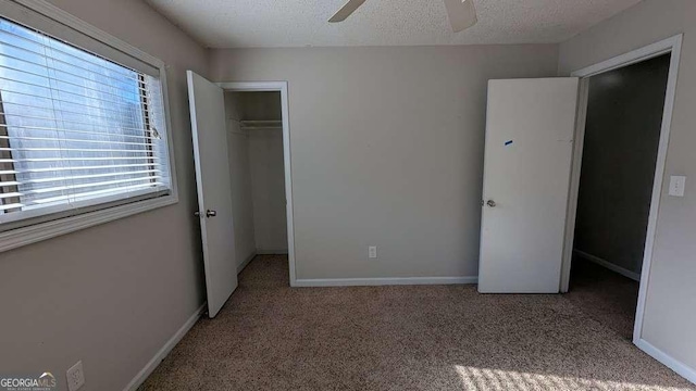 unfurnished bedroom with a textured ceiling, ceiling fan, a closet, and multiple windows