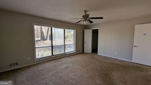 carpeted empty room with ceiling fan and a textured ceiling