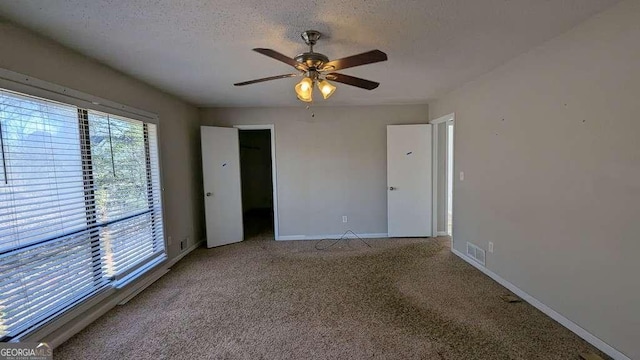 carpeted empty room featuring ceiling fan and a textured ceiling