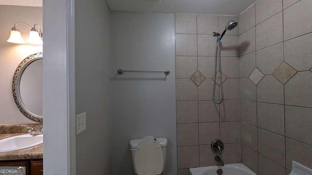 full bathroom with toilet, tiled shower / bath combo, and vanity