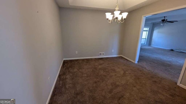 empty room with ceiling fan with notable chandelier and dark carpet