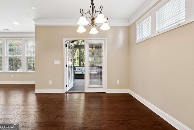 unfurnished dining area featuring dark hardwood / wood-style floors, crown molding, and a notable chandelier