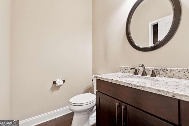 bathroom with toilet, hardwood / wood-style flooring, and vanity