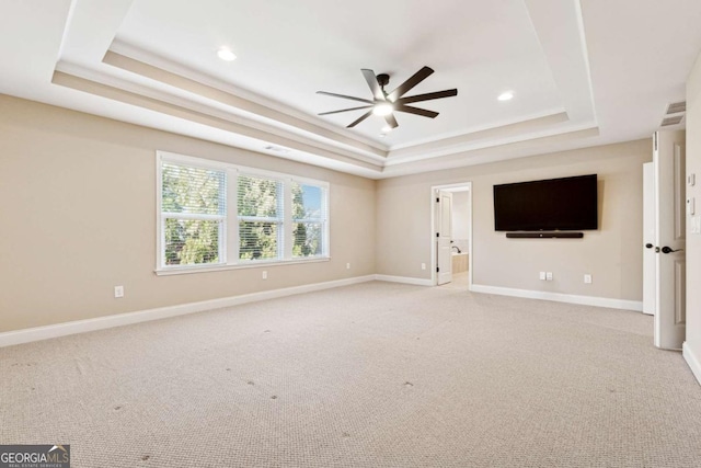 unfurnished living room with ceiling fan, light colored carpet, and a raised ceiling