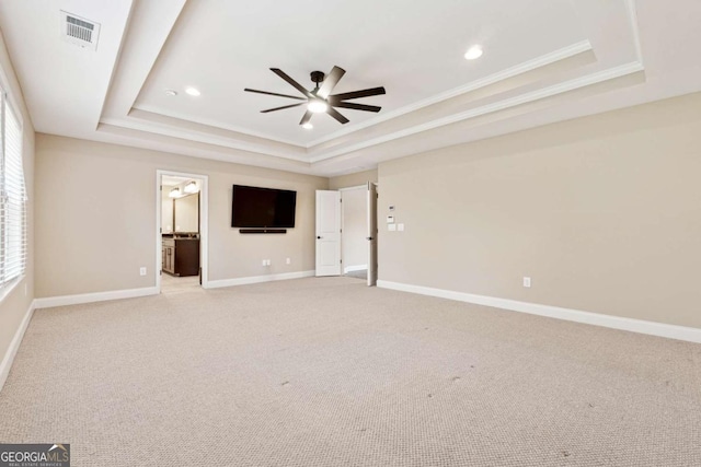 carpeted spare room with ceiling fan, a tray ceiling, and ornamental molding