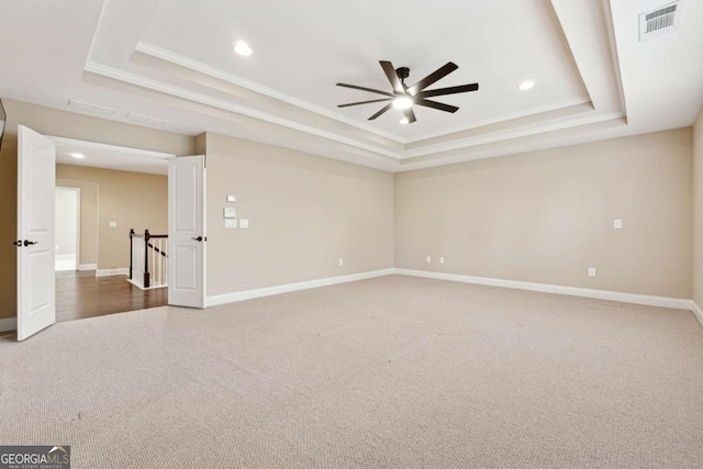 carpeted empty room featuring ceiling fan, ornamental molding, and a tray ceiling