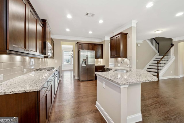 kitchen with appliances with stainless steel finishes, decorative backsplash, dark hardwood / wood-style floors, light stone countertops, and sink