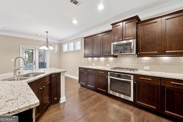 kitchen featuring appliances with stainless steel finishes, decorative light fixtures, sink, backsplash, and a chandelier