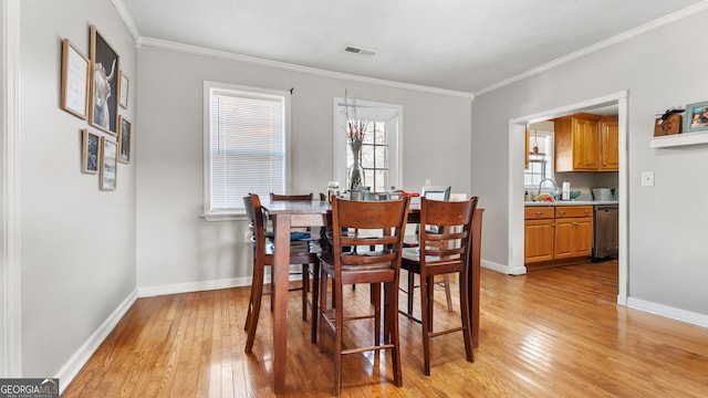 dining room featuring sink, crown molding, and light hardwood / wood-style flooring