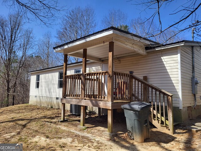 view of front of house with crawl space, a deck, metal roof, and a detached carport